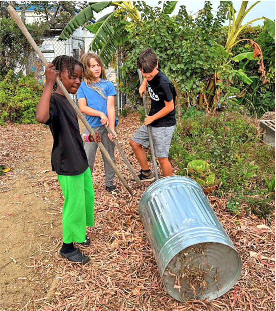 Will Rogers students raking compost into a container